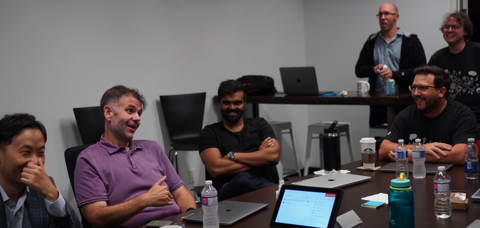 Four coworkers seated at a table smiling, laughing, or talking.