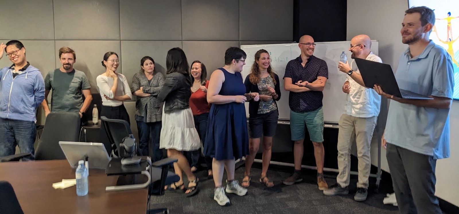 About 10 people lined up on one side of a conference room talking.