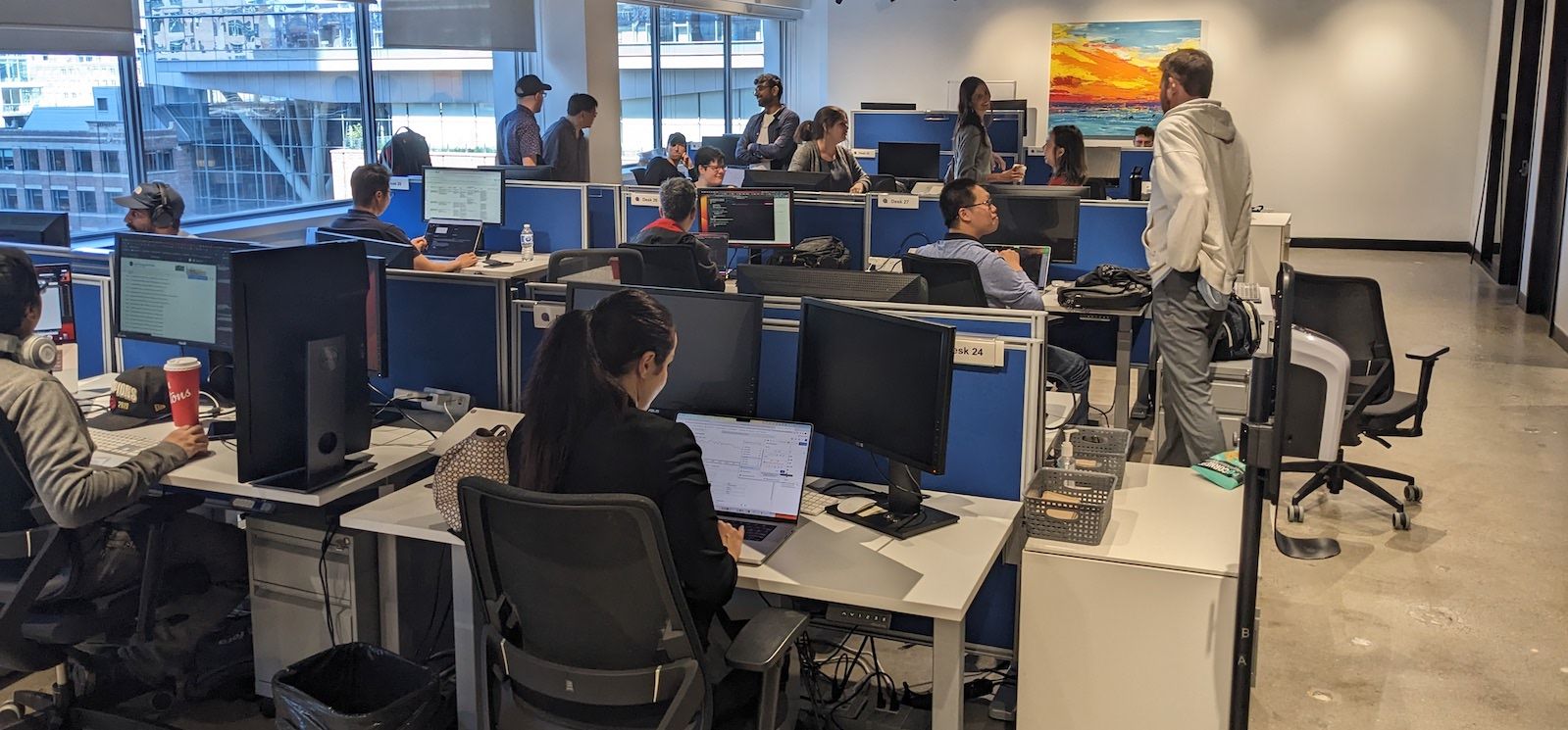 An open office area with coworkers sitting at desks with monitors.