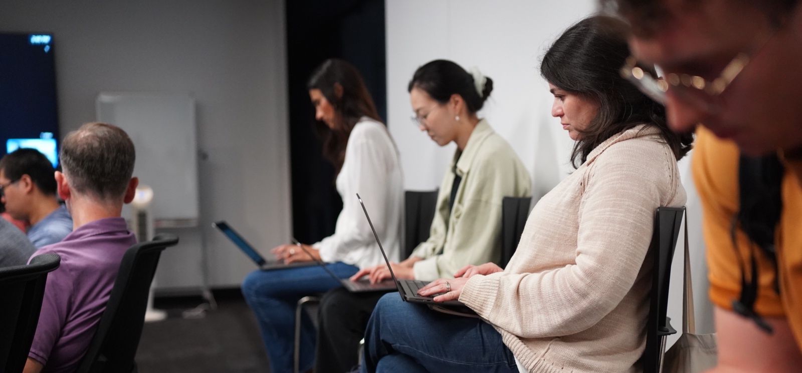 Three coworkers seated on stools working on their laptops.